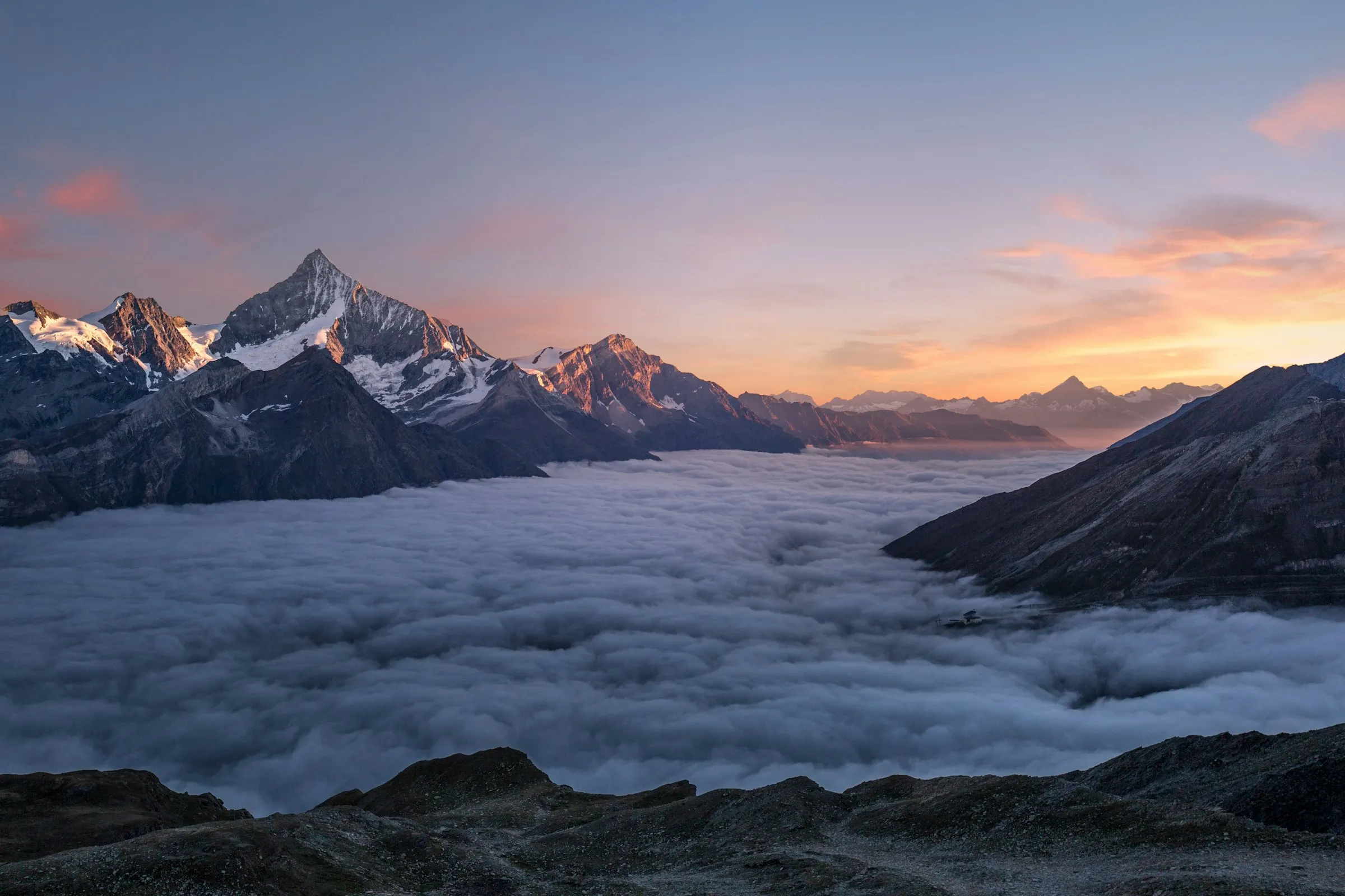 Berggipfel ragen bei Sonnenaufgang aus einem Meer aus Wolken