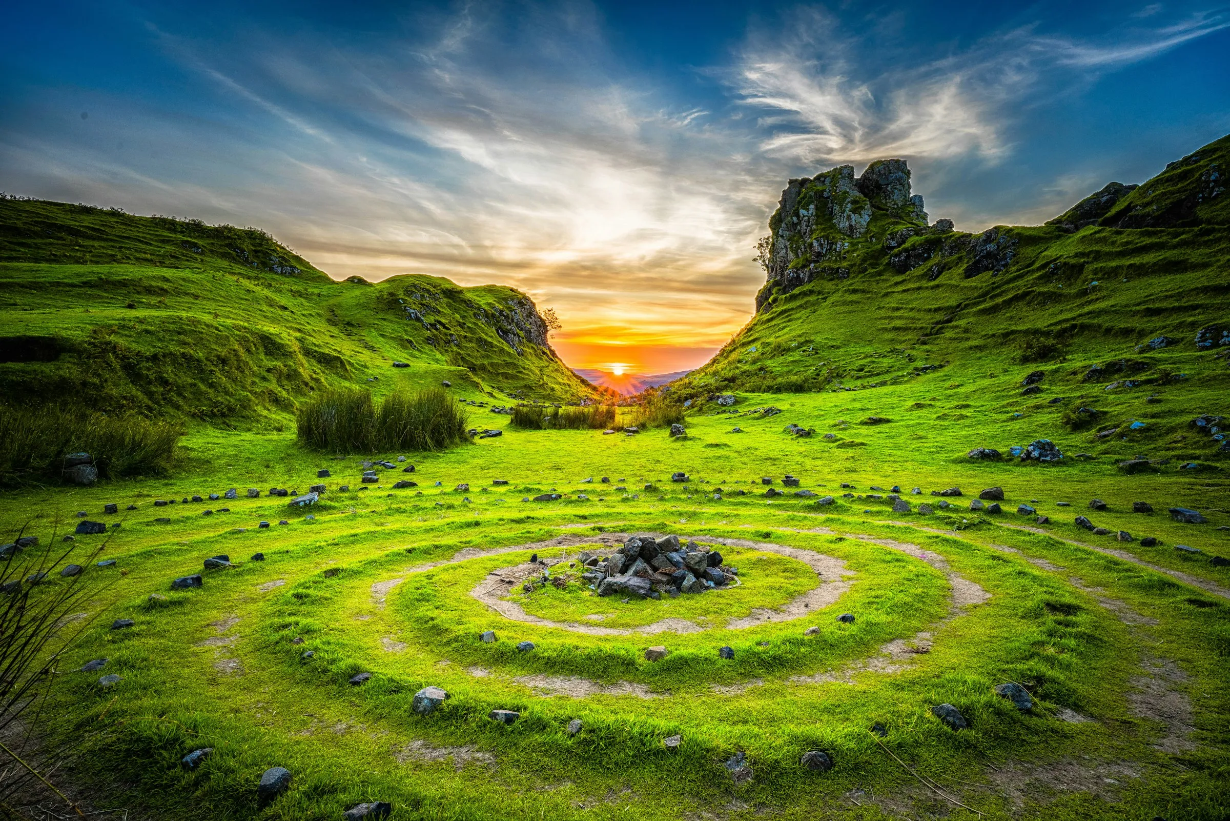 Grüne Hügel mit Steinspirale bei Sonnenuntergang