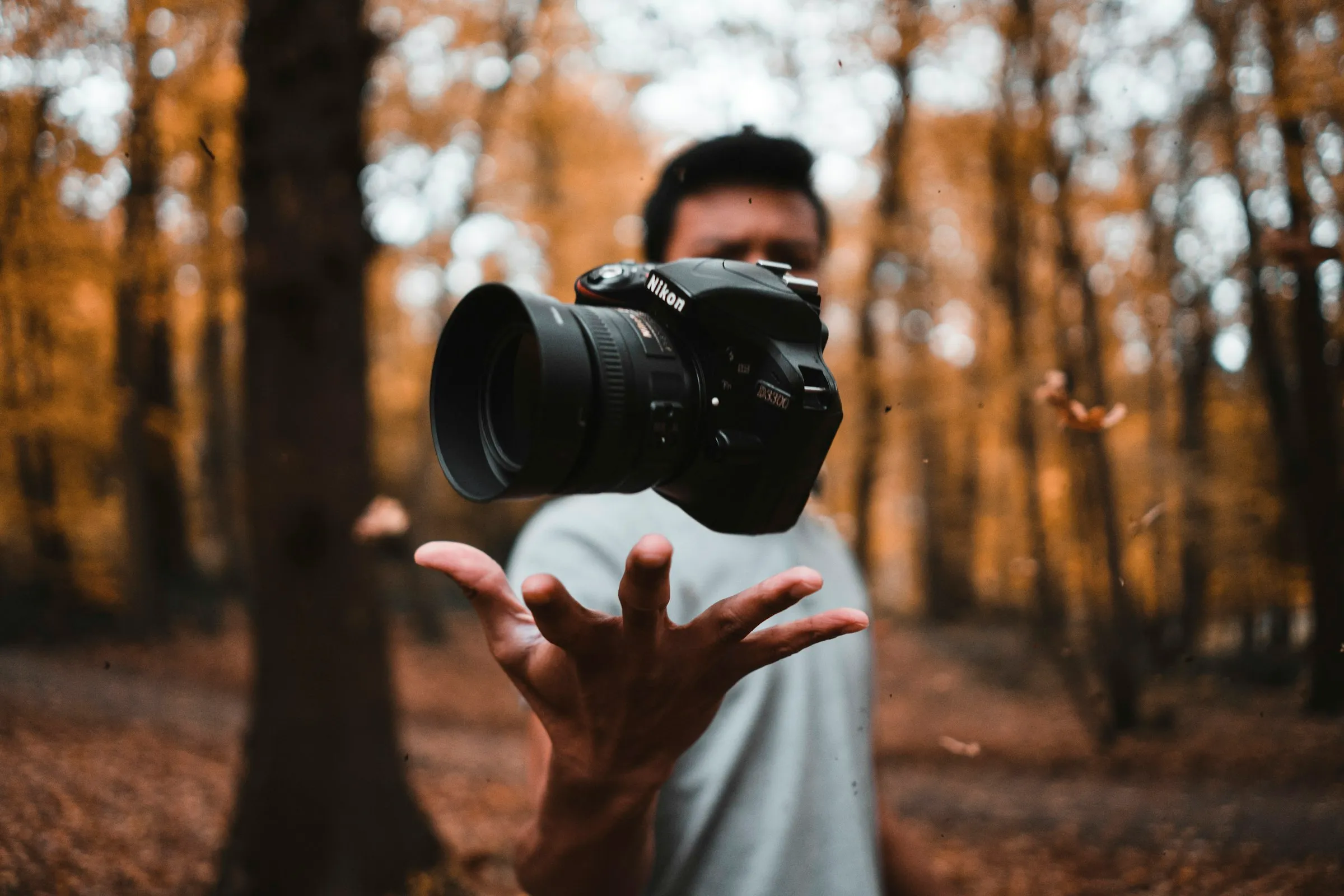 Fotograf hält seine Kamera in einem herbstlichen Wald