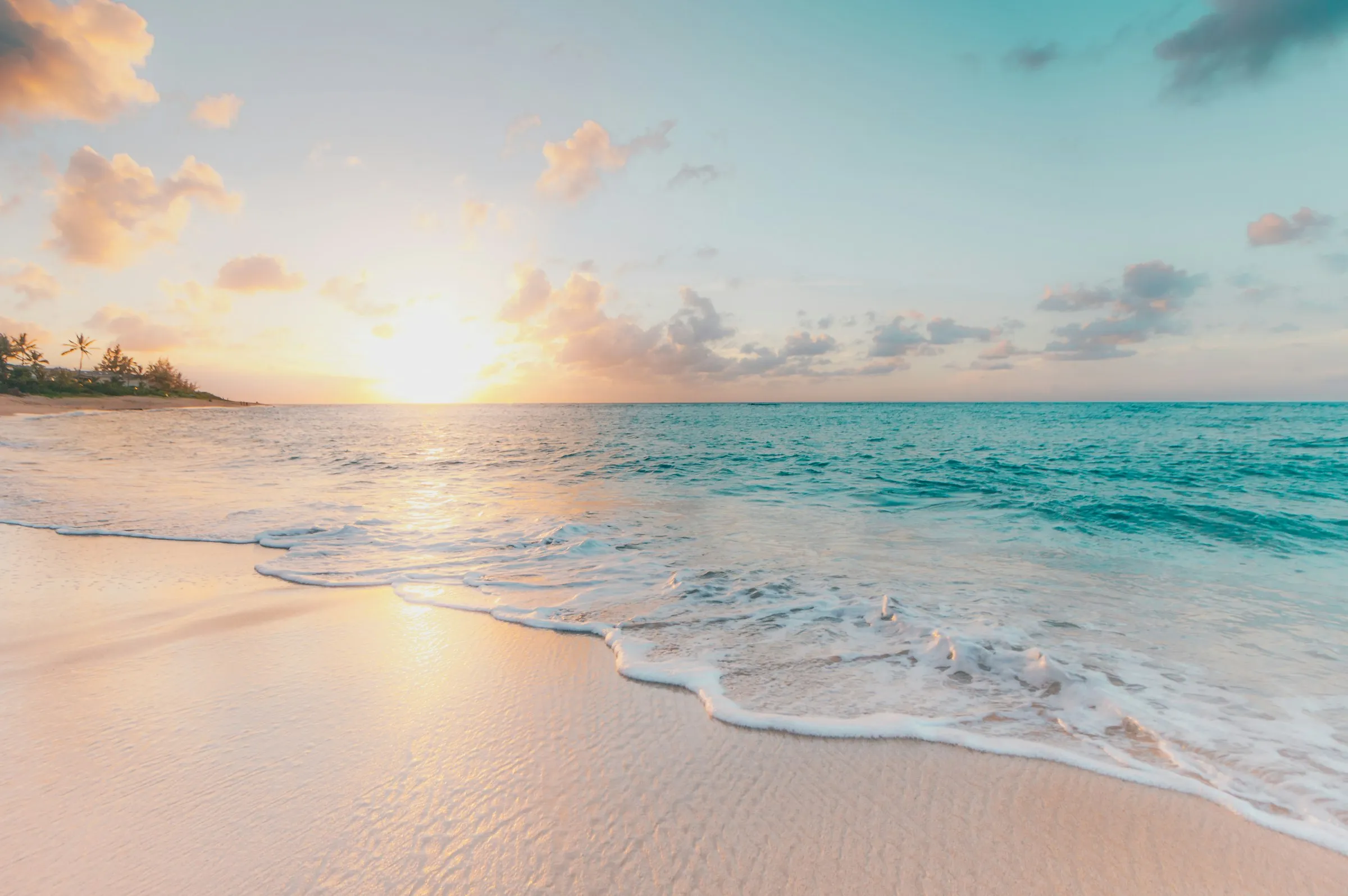 Sonnenuntergang an einem Sandstrand mit Wellen