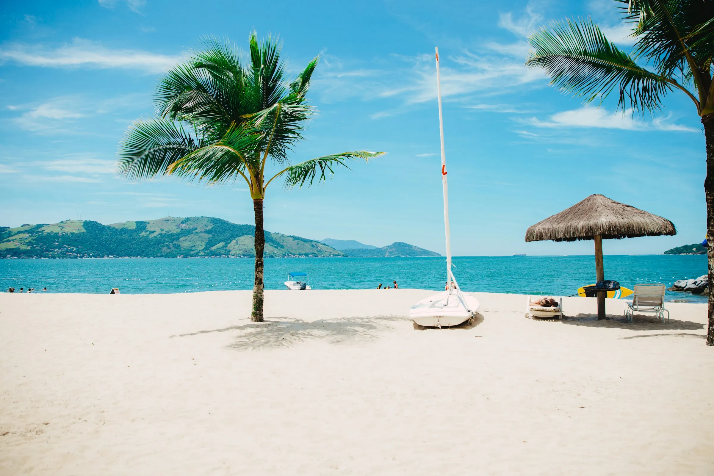 Palmen und Sonnenschirm an einem weißen Strand
